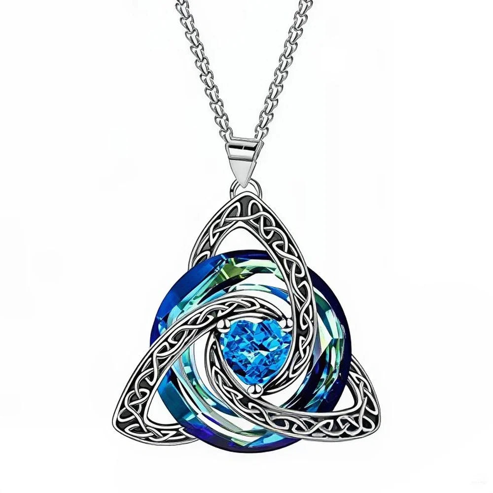 A silver Celtic knot triquetra pendant necklace featuring a central round blue crystal surrounded by layered iridescent blue and green swirled crystals, suspended from a silver chain on a white background.