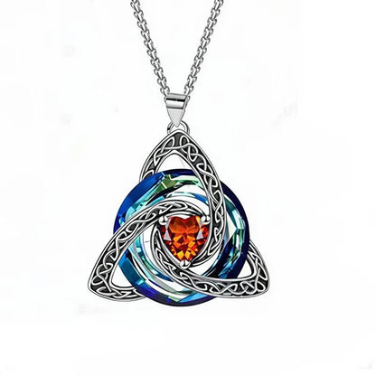 A silver Celtic triquetra knot pendant necklace featuring a central heart-shaped orange crystal surrounded by layered blue and green iridescent circular elements, suspended from a silver chain on a white background.