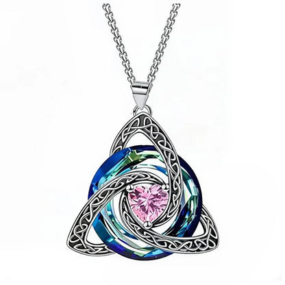 A silver Celtic knot triquetra pendant necklace featuring a central faceted pink heart-shaped crystal surrounded by layered blue and green iridescent rings, suspended from a silver chain on a white background.