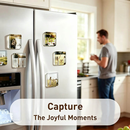 A white stainless steel refrigerator in a kitchen setting, decorated with several square clear magnets holding printed photos. A blurred man stands in the background near a window.