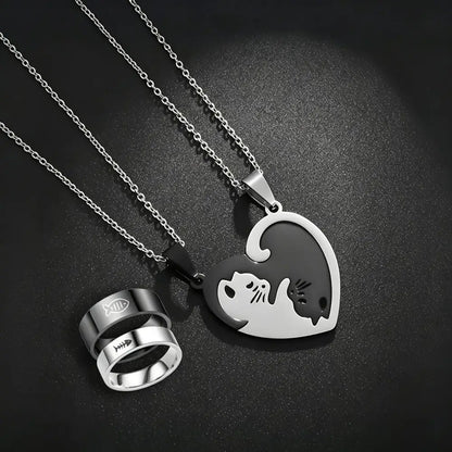 Two silver-toned necklaces and matching rings displayed on a dark textured background. One necklace has a heart-shaped pendant split into white and black halves forming a cat and dog silhouette.