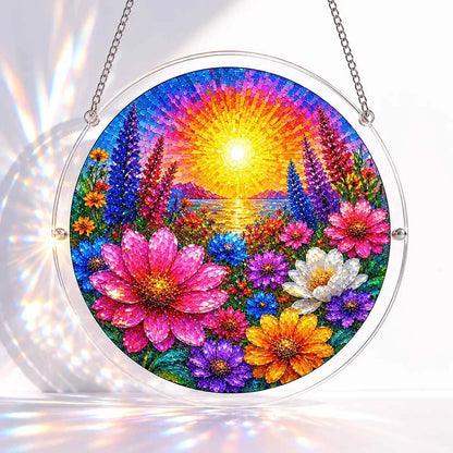 A round acrylic suncatcher of a mosaic style radiant sun over a colorful field of pink orange and purple flowers