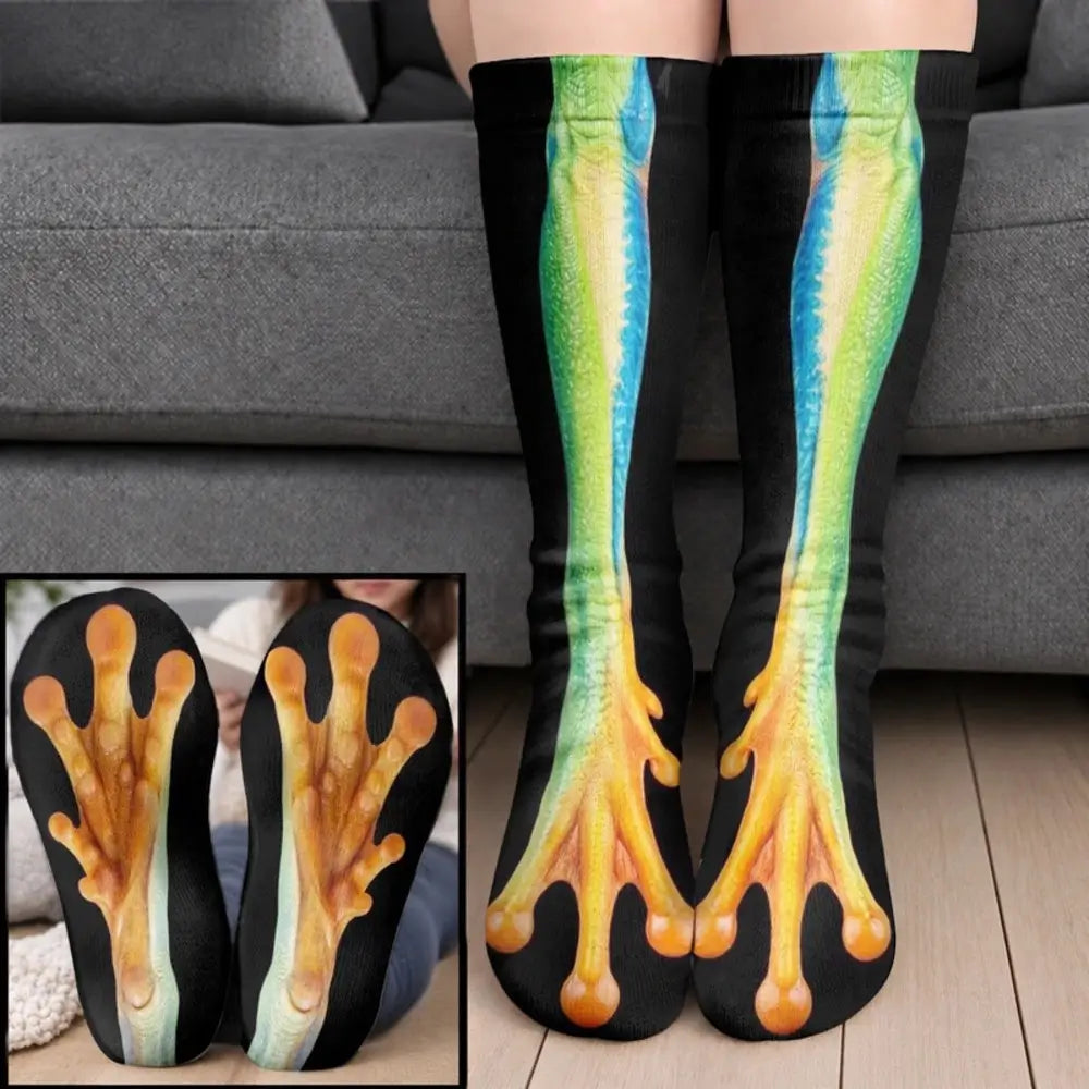 Green and blue frog leg socks with orange webbed toes worn on legs before a gray sofa