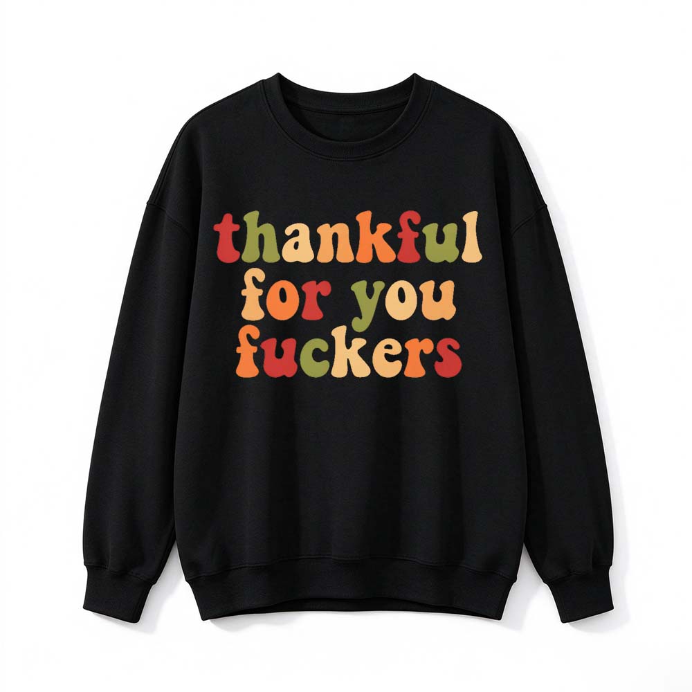 A black crew neck sweatshirt printed with three lines of warm colored retro Thanksgiving lettering on a white background