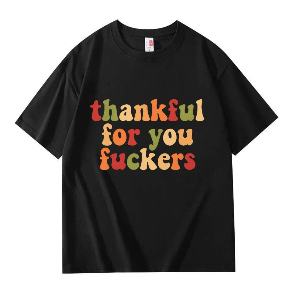 A black crew neck T-shirt with three lines of warm colored retro Thanksgiving lettering on a white background