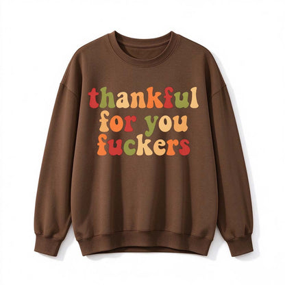 A dark brown crew neck sweatshirt printed with three lines of retro multicolor Thanksgiving lettering on a white background
