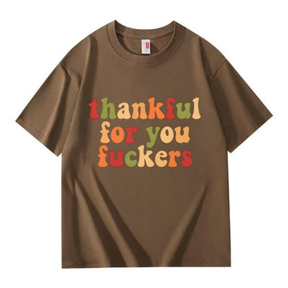 A dark brown crew neck T-shirt with three lines of retro multicolor Thanksgiving lettering on a white background