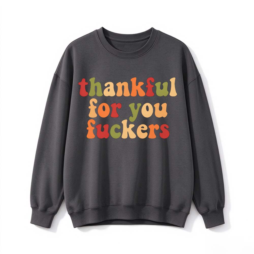 A dark gray crew neck sweatshirt printed with three lines of retro multicolor Thanksgiving lettering on a white background