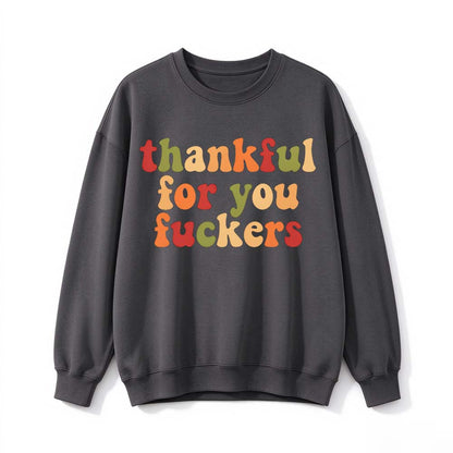 A dark gray crew neck sweatshirt printed with three lines of retro multicolor Thanksgiving lettering on a white background