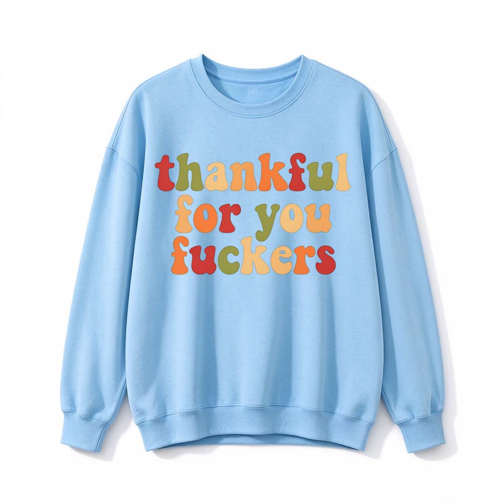A light blue crew neck sweatshirt printed with three lines of retro multicolor Thanksgiving lettering on a white background