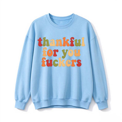 A light blue crew neck sweatshirt printed with three lines of retro multicolor Thanksgiving lettering on a white background