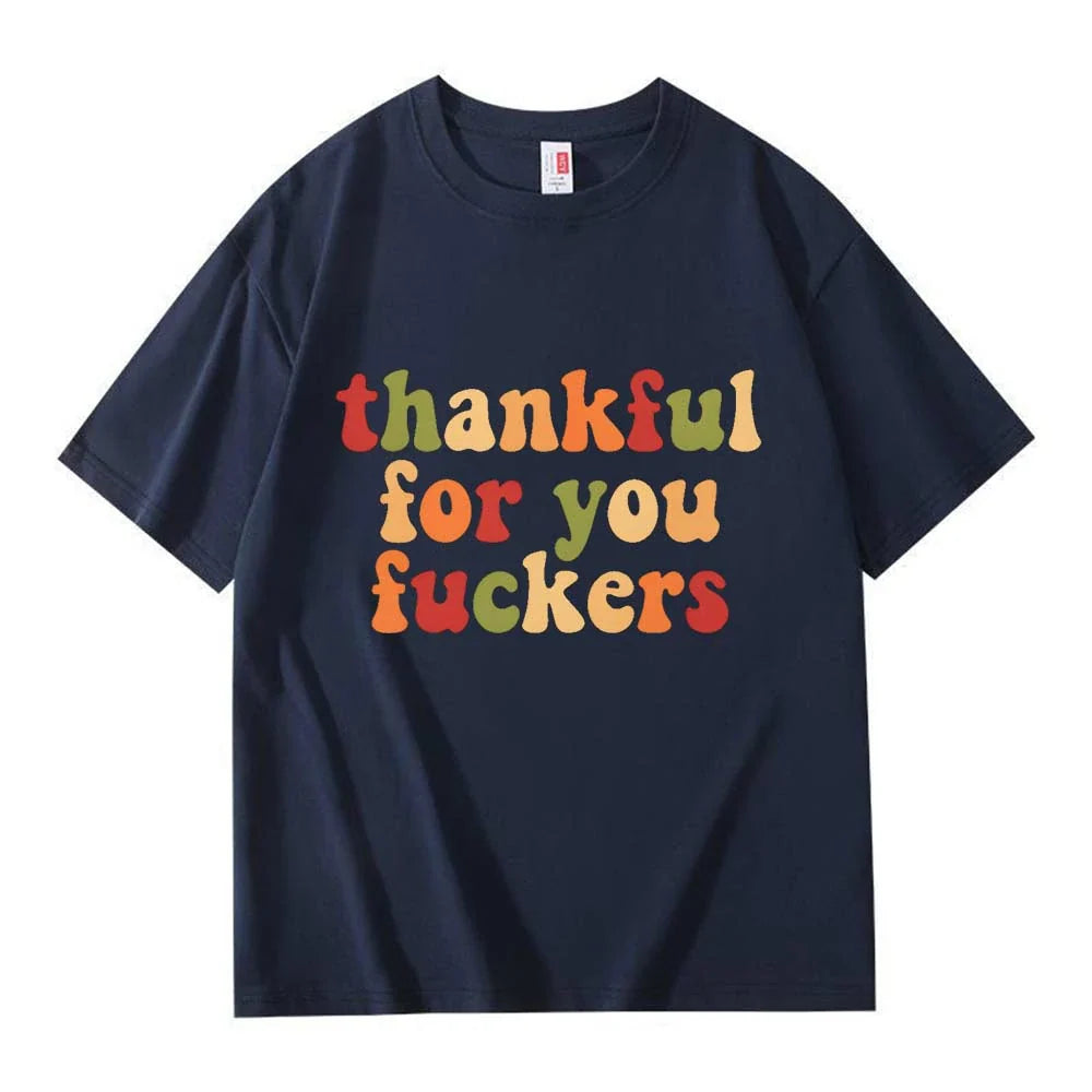 A navy blue crew neck T-shirt with three lines of retro multicolor Thanksgiving lettering on a white background