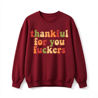 A wine red crew neck sweatshirt printed with three lines of retro multicolor Thanksgiving lettering on a white background