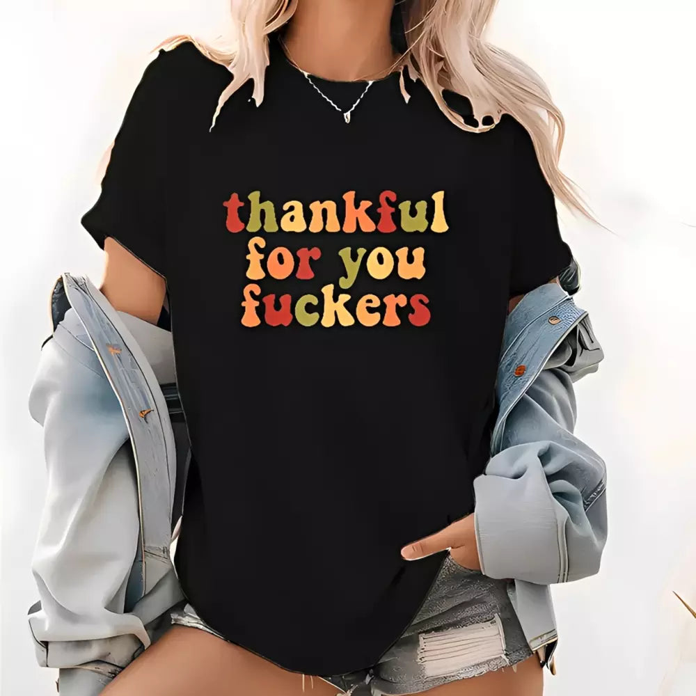 A blonde woman wearing a black T-shirt with colorful Thanksgiving lettering under a light blue denim jacket