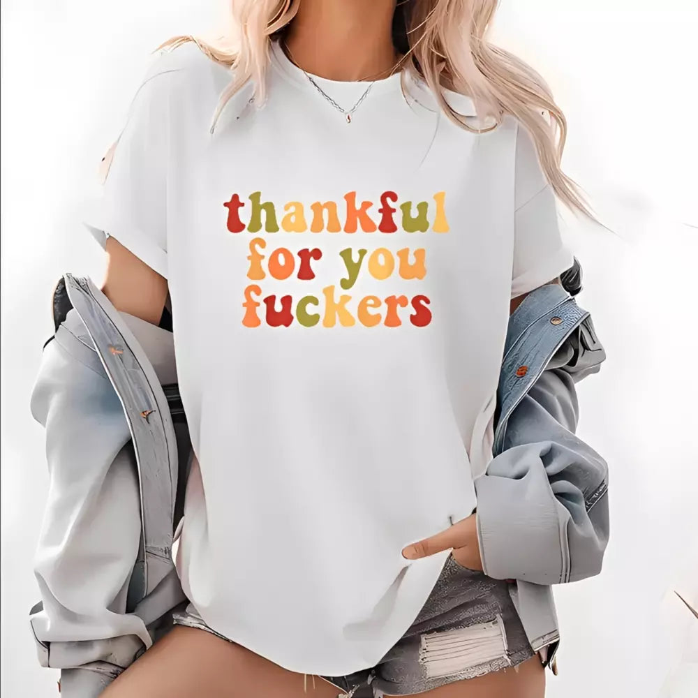 A blonde woman wearing a white T-shirt with multicolor Thanksgiving lettering loosely over a light blue denim jacket