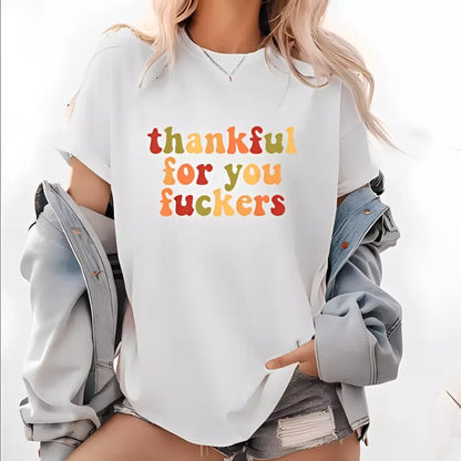 A blonde woman wearing a white T-shirt with multicolor Thanksgiving lettering loosely over a light blue denim jacket