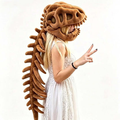 A woman wearing a large brown dinosaur skull and spine plush costume headpiece, posed against a plain white background while pointing with both hands.