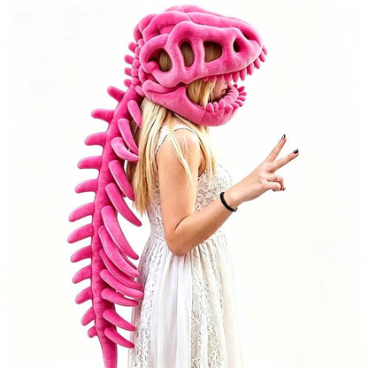 A woman in a white lace dress wearing a large pink dinosaur skull and spine plush costume hat, posing against a plain white background.