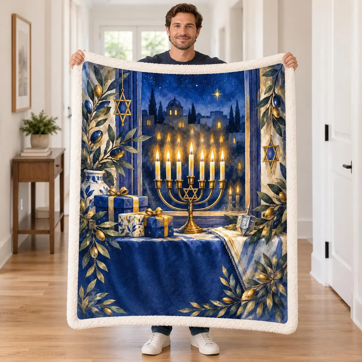 A man holds up the plush white-edged menorah blanket to display its colorful Hanukkah themed print in a bright hallway
