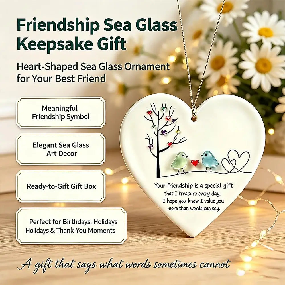 Heart-shaped sea glass keepsake ornament necklace with a printed design of two birds and a tree, shown hanging on a chain against a warm floral and string-light background. The image includes promotional text describing it as a friendship sea glass keepsake gift and listing features such as meaningful friendship symbol, elegant sea glass art decor, ready-to-go gift box, and perfect for birthdays, holidays, and thank-you moments.