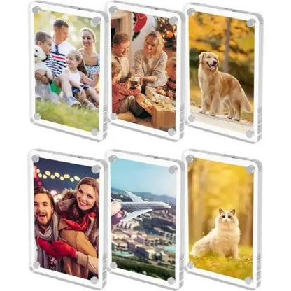 Six clear acrylic photo frames arranged in two rows on a white background, each displaying a different printed photo. The photos include family scenes, a dog, couple portraits, an airplane over a city, and a cat in a yellow field.