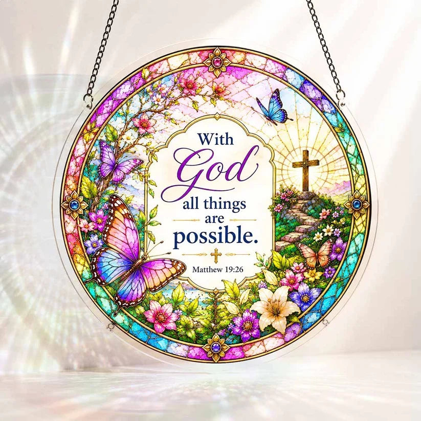 A round acrylic suncatcher decorated with butterflies flowers and a cross featuring the bible verse with God all things are possible
