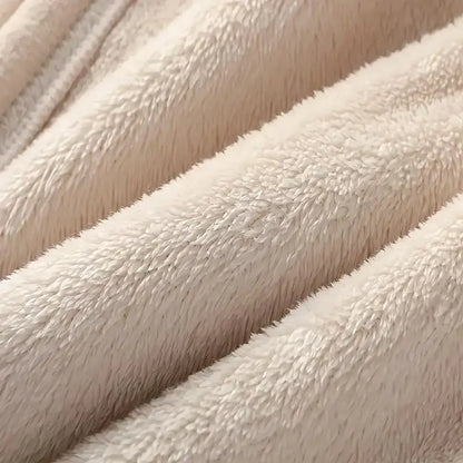 Close-up of a soft plush fabric in a warm off-white or cream color, showing the texture and folds of the material.