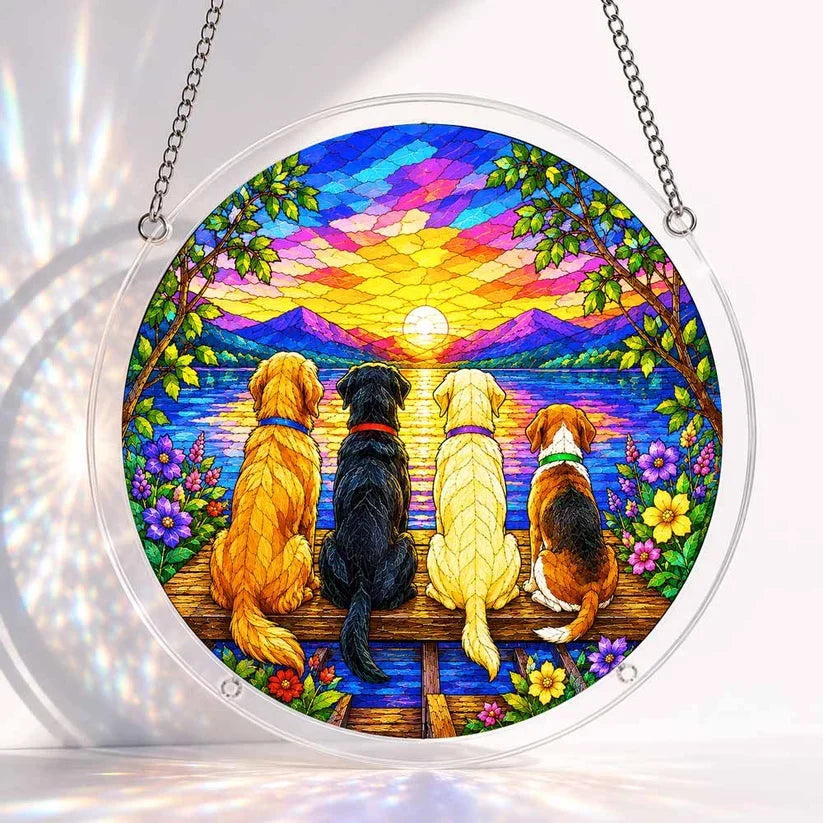 A round acrylic suncatcher showing four dogs sitting on a wooden dock watching the sunset over a lake and mountains