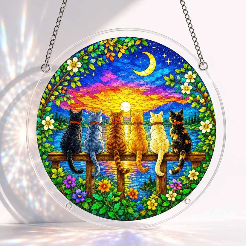 A round acrylic suncatcher showing six cats sitting on a wooden fence at twilight overlooking a lake under a crescent moon