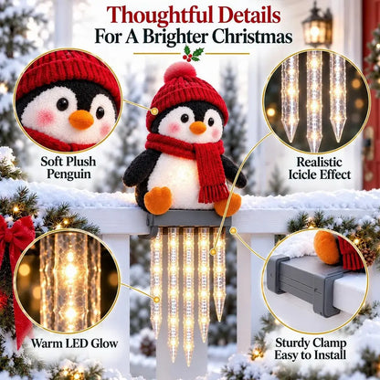 A plush penguin Christmas decoration wearing a red knit hat and scarf, mounted on a snowy porch railing with warm LED icicle lights hanging below. The image includes callout circles highlighting soft plush texture, realistic icicle lights, warm LED glow, and a sturdy clamp for easy installation.