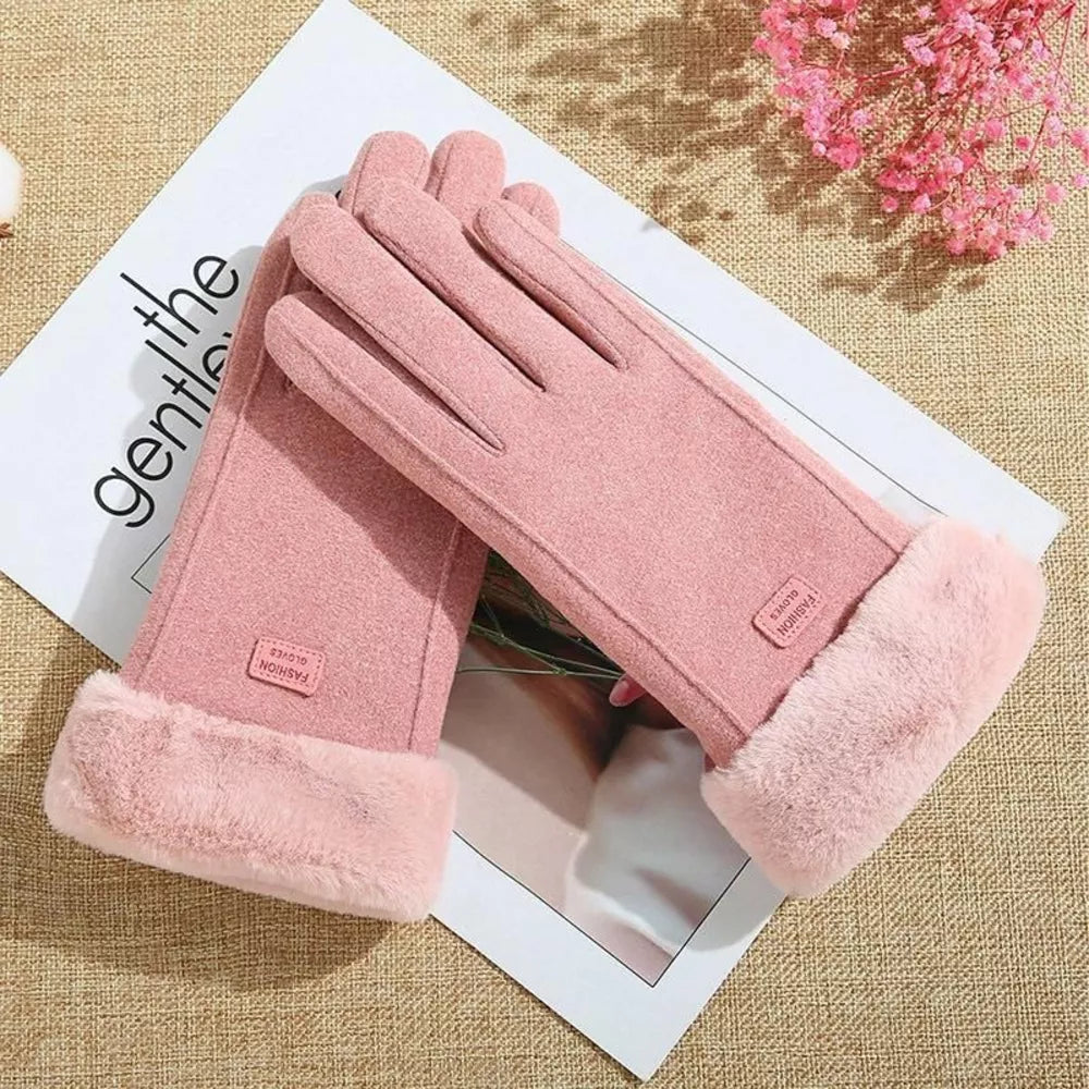 A pair of dusty pink winter gloves with plush faux-fur cuffs, arranged on a white printed card over a beige woven fabric.